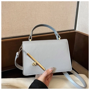 Close-up of light grey lychee leather handbag with gold metal bar and ring twist lock