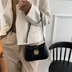 Classic black leather shoulder bag with gold metal clasp shown on a model for spring outfits