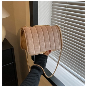 Detail of velvet chain crossbody bag with vertical quilting and gold corner accents