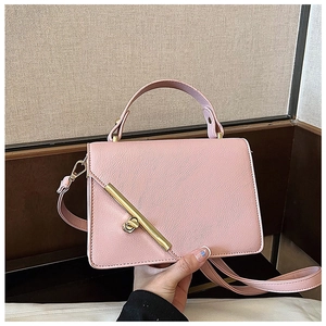 Close-up of pink litchi grain leather handbag with gold metal bar clasp detail