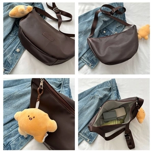 Detail view of brown crescent crossbody bag showing interior capacity and plush charm