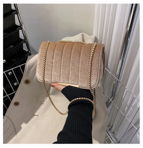 Detail of champagne velvet crossbody bag showing vertical quilting and gold chain strap