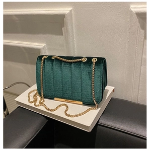 Close-up of deep green velvet crossbody bag featuring vertical quilting and gold chain