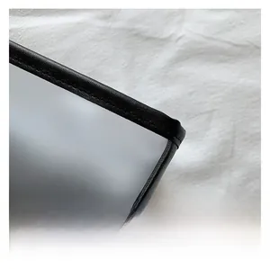 Close-up of gray translucent frosted fabric with black leather trim on a tote bag
