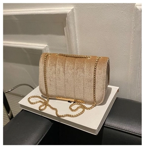 Detailed view of champagne velvet crossbody bag with vertical quilting and gold chain strap