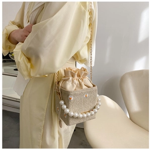 Detailed view of straw bucket bag with daisy embroidery and elegant pearl handle strap