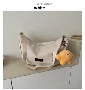 Detail of off-white crescent crossbody bag with yellow star plush charm and textile strap