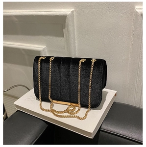 Close-up of black velvet quilted shoulder bag with gold chain strap and metal trim