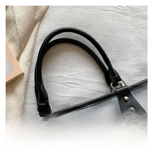 Detail of reinforced black handle with silver rivets and frosted translucent tote material