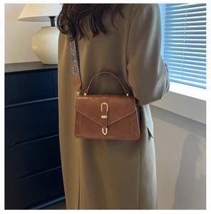 Dettaglio borsa vintage marrone con fibbia a U dorata e tracolla in tessuto colorato