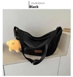 Detail of black crescent bag with wide strap and yellow star plush charm accessory