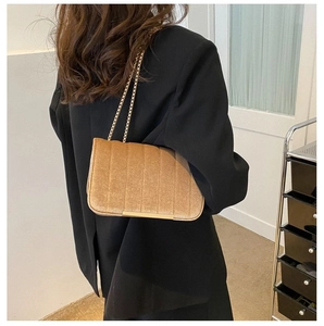 Detail of champagne velvet crossbody bag with gold chain strap and elegant stitching