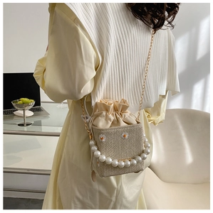 Detail of straw woven bucket bag with pearl handle and daisy floral embroidery