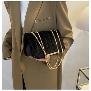 Detail view of black velvet quilted crossbody bag with gold chain and metal trim edges