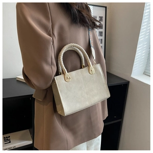 Dettaglio borsa squadrata beige con manico intrecciato e tracolla geometrica colorata