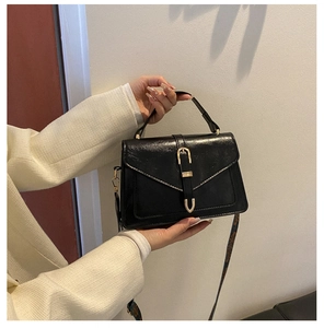Dettaglio borsa vintage in vernice nera con fibbia dorata e tracolla con decorazioni