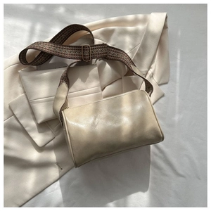 Detail einer cremefarbenen Ledertasche mit breitem Vintage-Jacquard-Riemen und Geometriemuster
