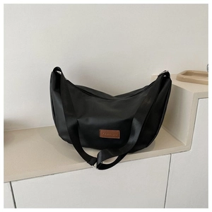 Detail of black crescent moon bag featuring nylon fabric and a brown leather logo tag