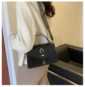 Dettaglio della borsa a busta nera vintage con fibbia dorata e tracolla larga decorata