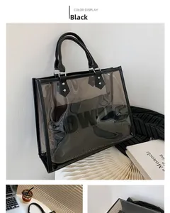 Detail of black transparent PVC tote bag with leather handles and inner pouch on desk