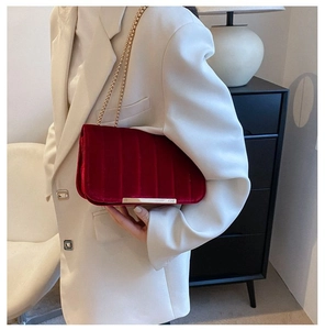 Detailed view of dark red velvet shoulder bag with vertical pleats and gold chain strap