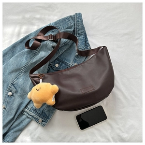 Detail of dark brown leather hobo bag with adjustable strap and plush croissant pendant