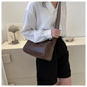 Braune Zylindertasche mit gewebtem breitem Schultergurt an einem Modell