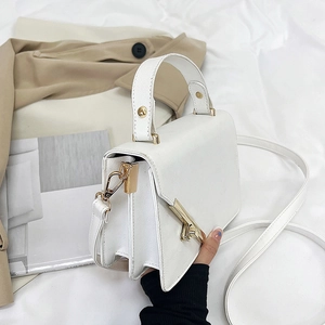White faux leather crossbody bag with gold hardware and top handle in minimalist style