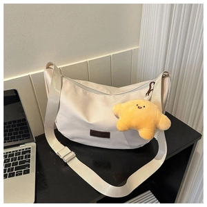 Close-up of cream crescent shoulder bag with leather patch and yellow star charm