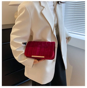 Detail view of burgundy velvet shoulder bag with gold chain strap and quilted texture