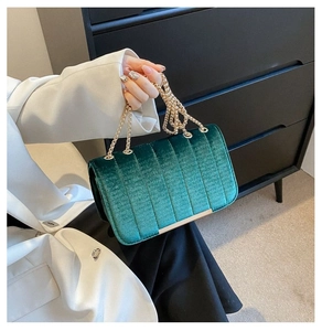 Detail view of emerald velvet crossbody bag with gold chain and vertical stitching