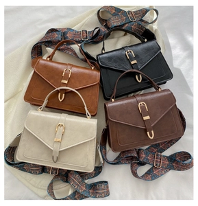 Dettaglio di borse quadrate vintage in vari colori con tracolla larga in stile boho