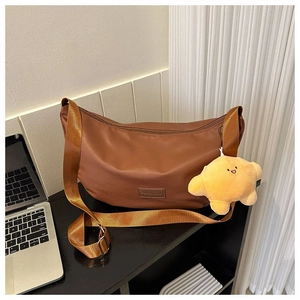 Brown moon bag with wide nylon strap and yellow star charm on a wooden table