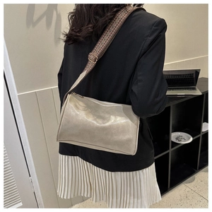 Detail eines breiten Jacquard-Gurts an einer cremefarbenen Tasche mit schwarzem Blazer