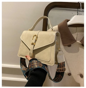 Dettaglio borsa beige con fibbia dorata a ferro di cavallo e tracolla larga stile etnico