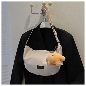 Detail of cream hobo bag featuring adjustable strap and a yellow star plush charm
