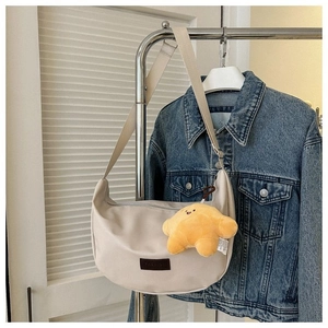 Detail of off-white crescent crossbody bag with star plush charm and fashion patch
