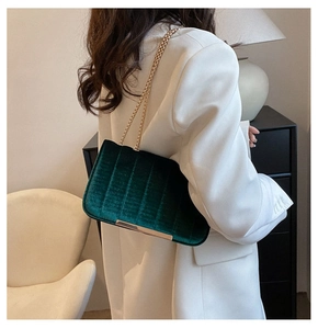 Close-up of green velvet crossbody bag with quilted pattern and gold chain strap detail