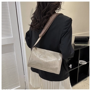 Detailansicht einer beigen Ledertasche mit braunem gewebtem breitem Schultergurt