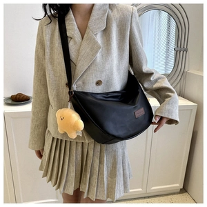 Detail of black crescent crossbody bag featuring a leather patch and star plush charm