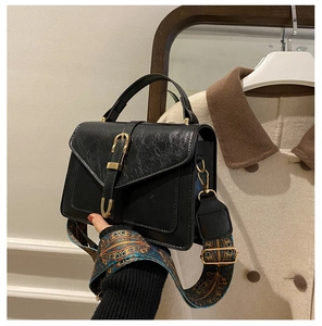 Dettaglio borsa vintage nera a busta con tracolla ricamata colorata e fibbia dorata