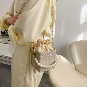 Daisy embroidered straw bucket bag with pearl handle and chain strap on a model