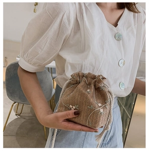 Détail d'un mini sac seau tissé avec broderies florales et fermeture par cordon en coton