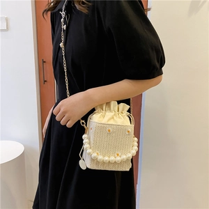 Straw bucket bag with daisy embroidery, pearl handle, and metal chain shoulder strap