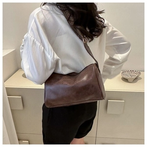 Detailansicht einer dunkelbraunen Vintage-Umhängetasche aus Leder an einem Model getragen