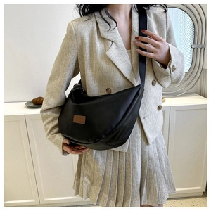 Detail of black crescent crossbody bag with minimalist square logo and nylon strap