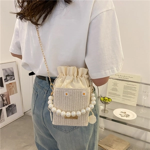 Beige straw bucket bag with daisy embroidery, pearl handle and golden chain strap