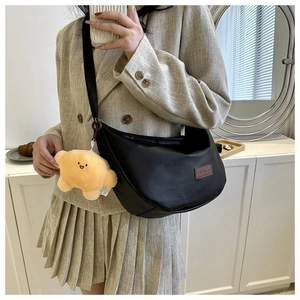 Detail of black half-moon crossbody bag with leather fashion tag and star charm accessory