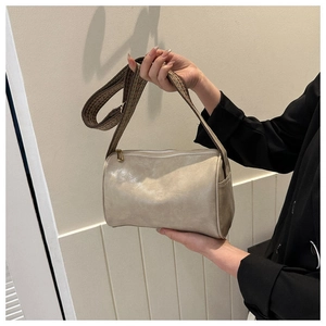 Nahaufnahme der cremefarbenen Zylindertasche mit einem breiten gewebten Retro-Gurt