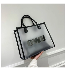 Detail view of transparent frosted tote bag with black leather handles and OWU lettering
